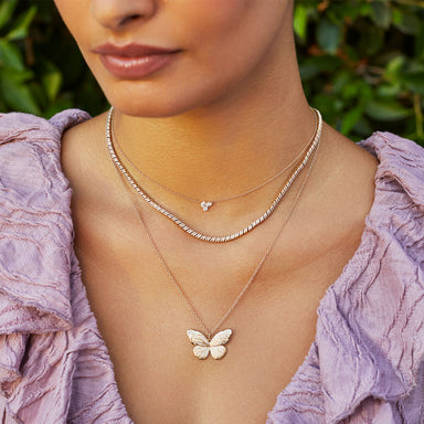 Triple Diamond Cluster Necklace in 14k rose gold styled on neck of model with diamond twist necklace and jumbo butterfly necklace