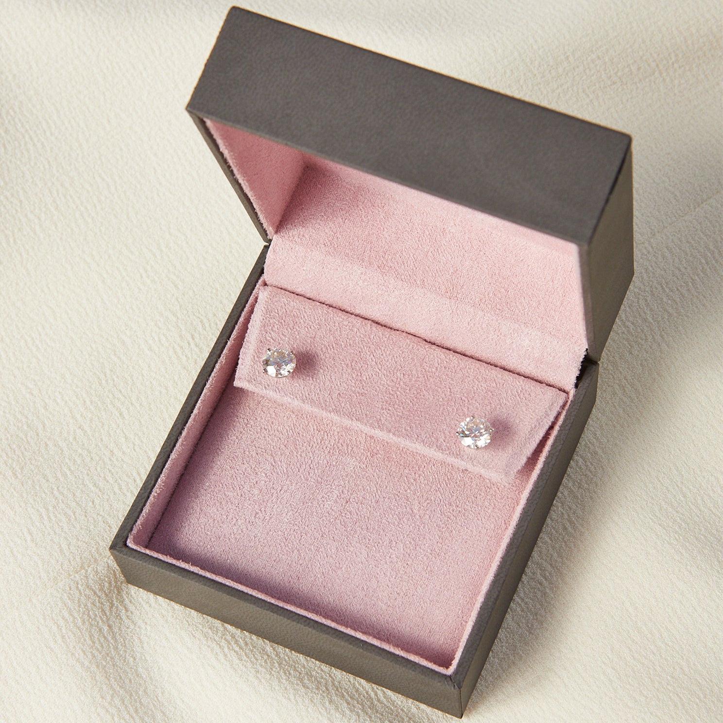 Round Diamond Solitaire Stud Earrings in platinum setting inside pink and grey jewelry packaging