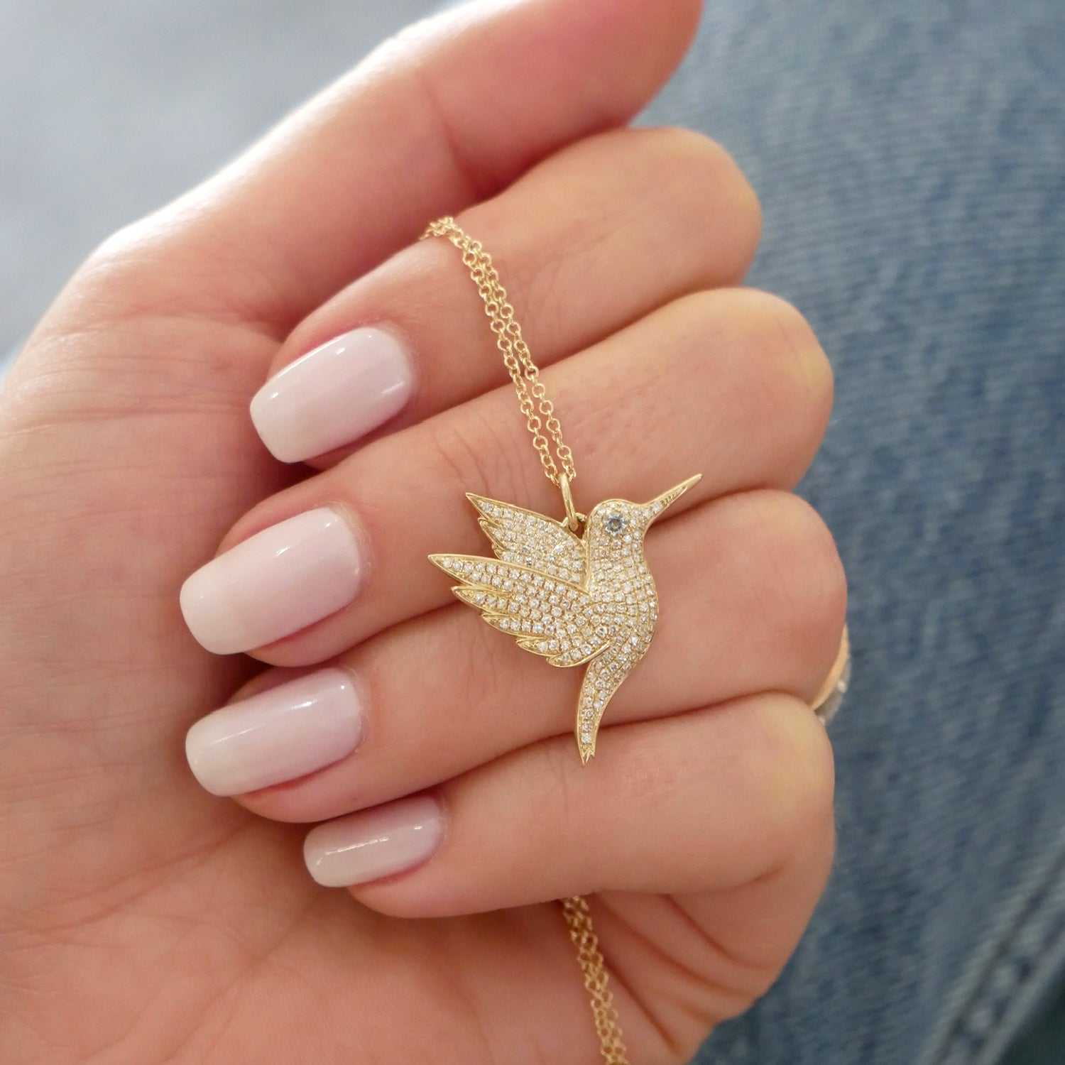 EF Collection 14k yellow gold hummingbird pendant necklace held in hand of model