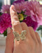 Pavé Diamond Jumbo Butterfly Ring in 14k yellow gold styled on finger of model in front of pink flowers