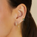 Pillow Chain Diamond Mini Huggie Earring in 14k yellow gold styled on second earring hole of model next to three earrings