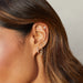 Diamond Crown Huggie Earring styled on ear of model with diamond earrings
