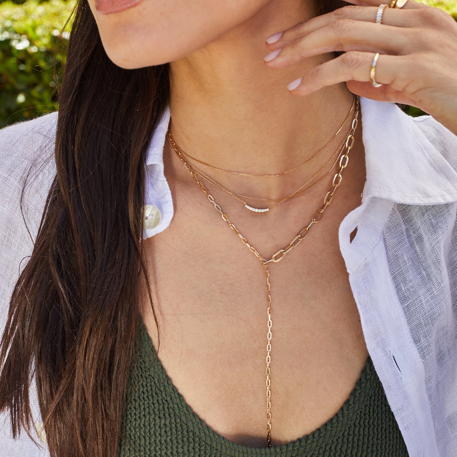 Graduated Chain Link Lariat Necklace in 14k yellow gold styled on neck of model with multiple gold necklaces