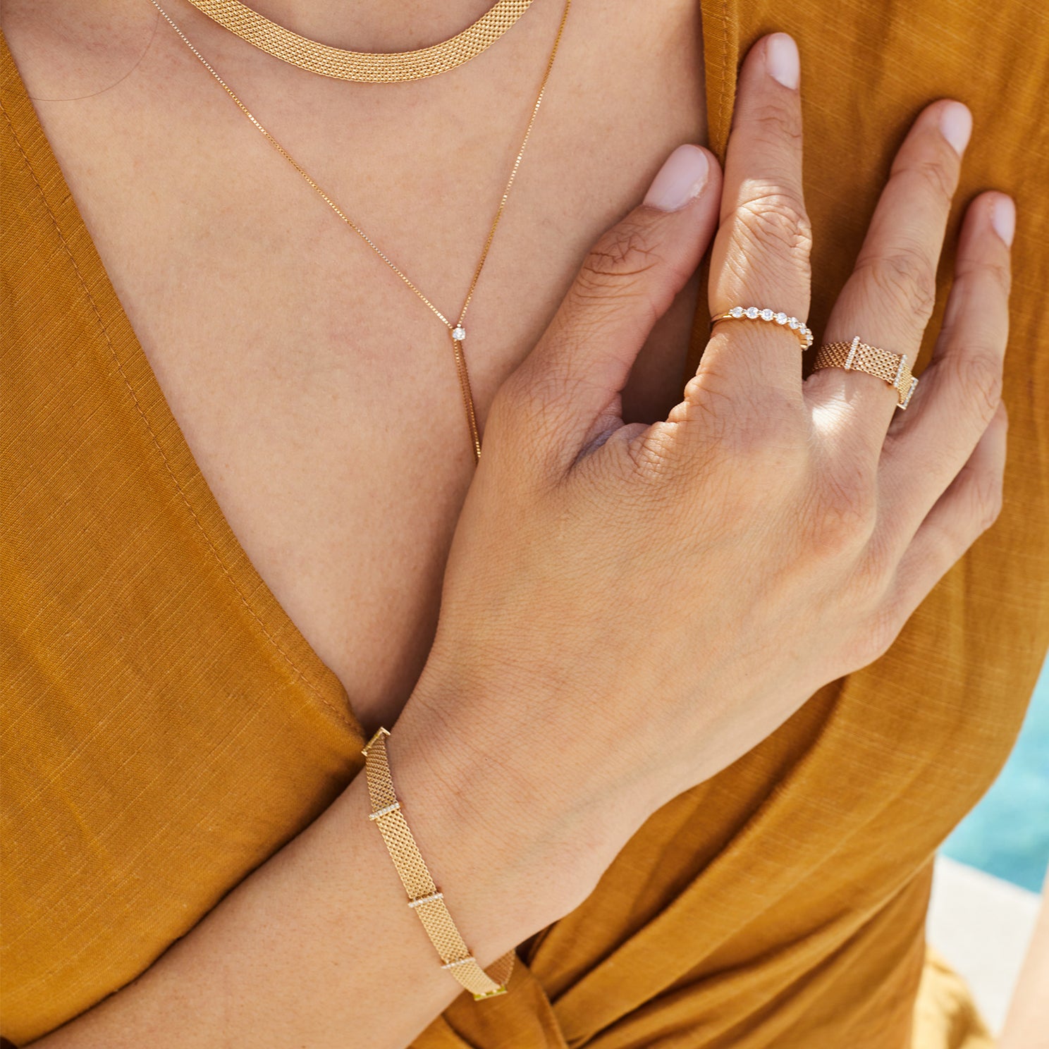 Diamond Bar Mesh Bracelet in 14k yellow gold styled on wrist of model and model wearing diamond rings and mustard yellow blouse
