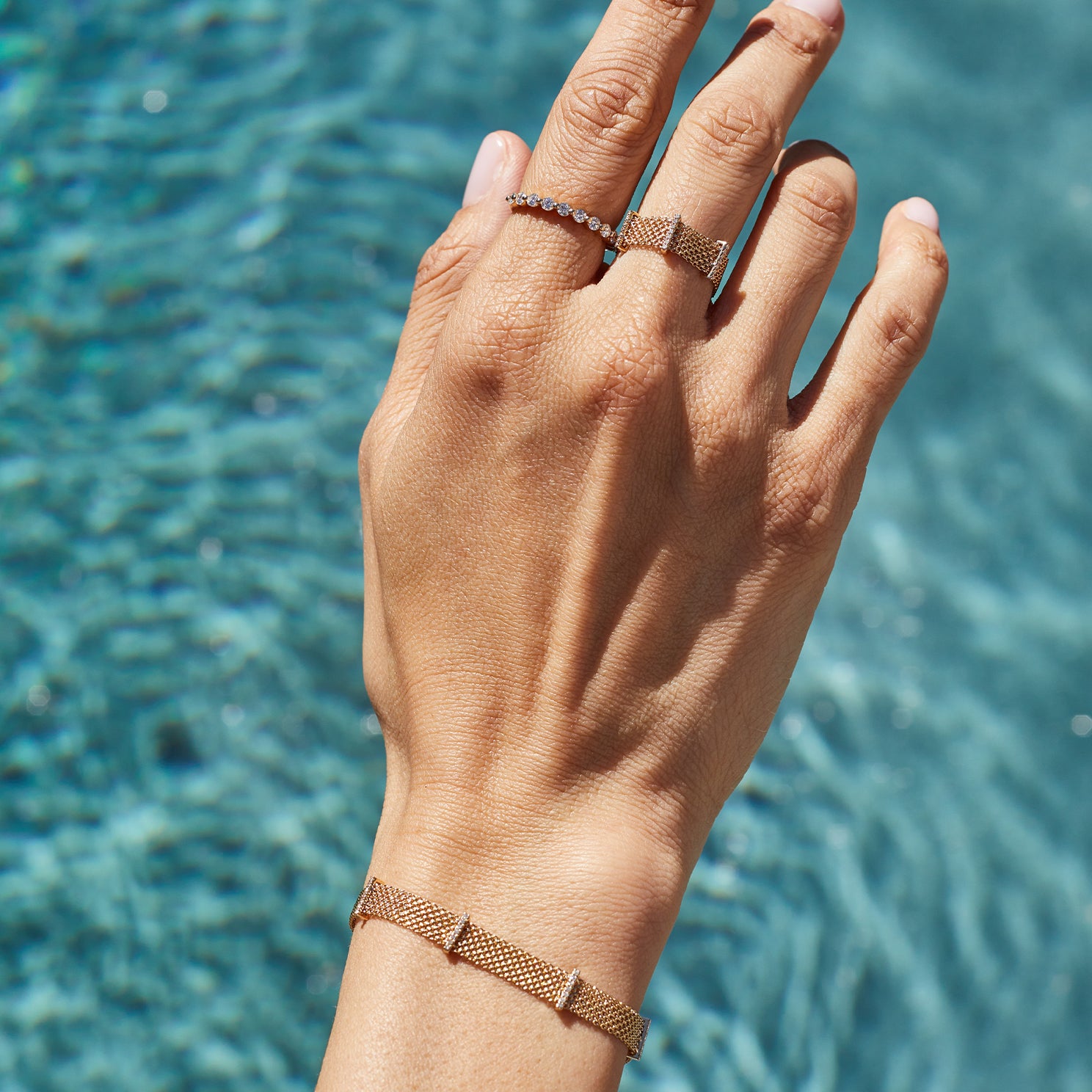 Diamond Bar Mesh Ring in 14k yellow gold styled on finger of model next to diamond ring with water rippling