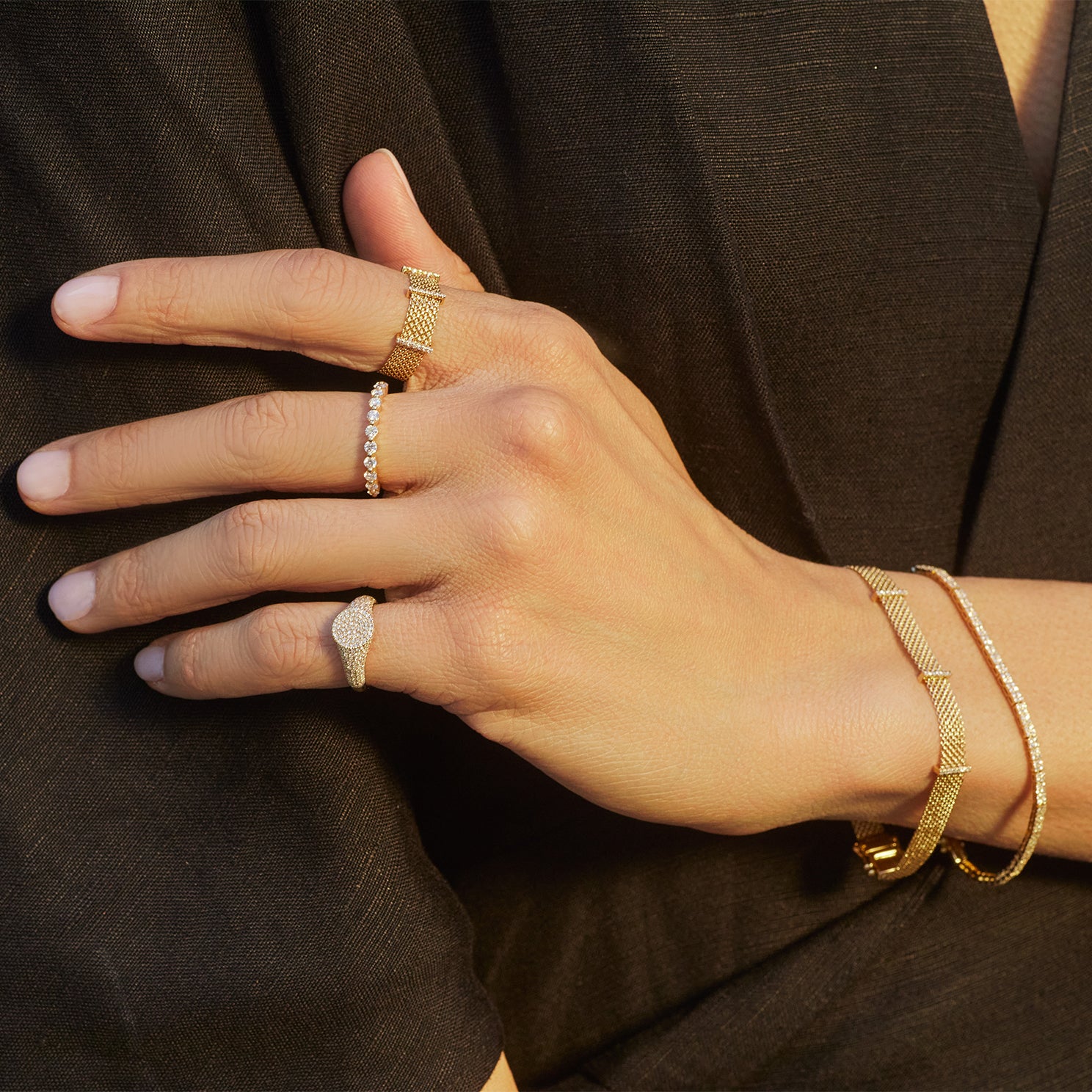 Diamond Bar Mesh Bracelet in 14k yellow gold styled on wrist of model with diamond rings styled on fingers of model and wearing black blouse