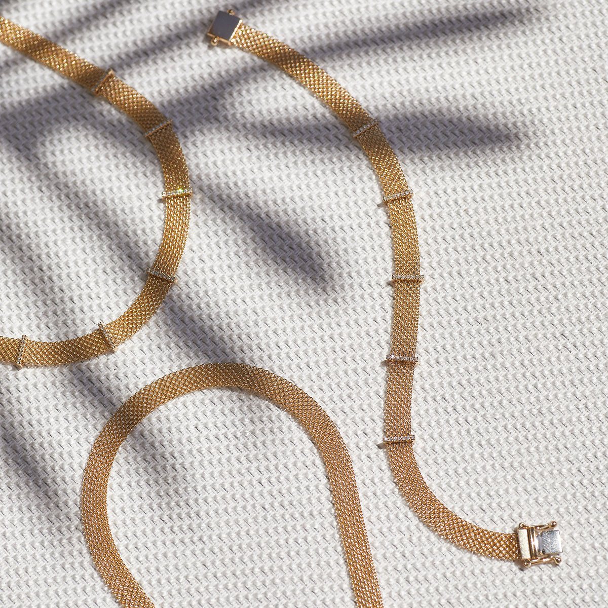 Gold Mesh Necklace in 14k yellow gold next to diamond bar necklace and diamond bar bracelet with palm tree shadow