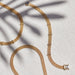 Gold Mesh Necklace in 14k yellow gold next to diamond bar necklace and diamond bar bracelet with palm tree shadow