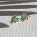 Emerald Wild Palm Stud Earring in 14k yellow gold on top of textured cloth