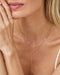 Close-up of a woman wearing gold necklaces and earrings with a blurred background