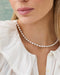 Close-up of a woman wearing a pearl necklace and earrings with a blurred background