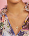Cherry Blossom Necklace in 14k yellow gold styled on neck of model in floral blouse
