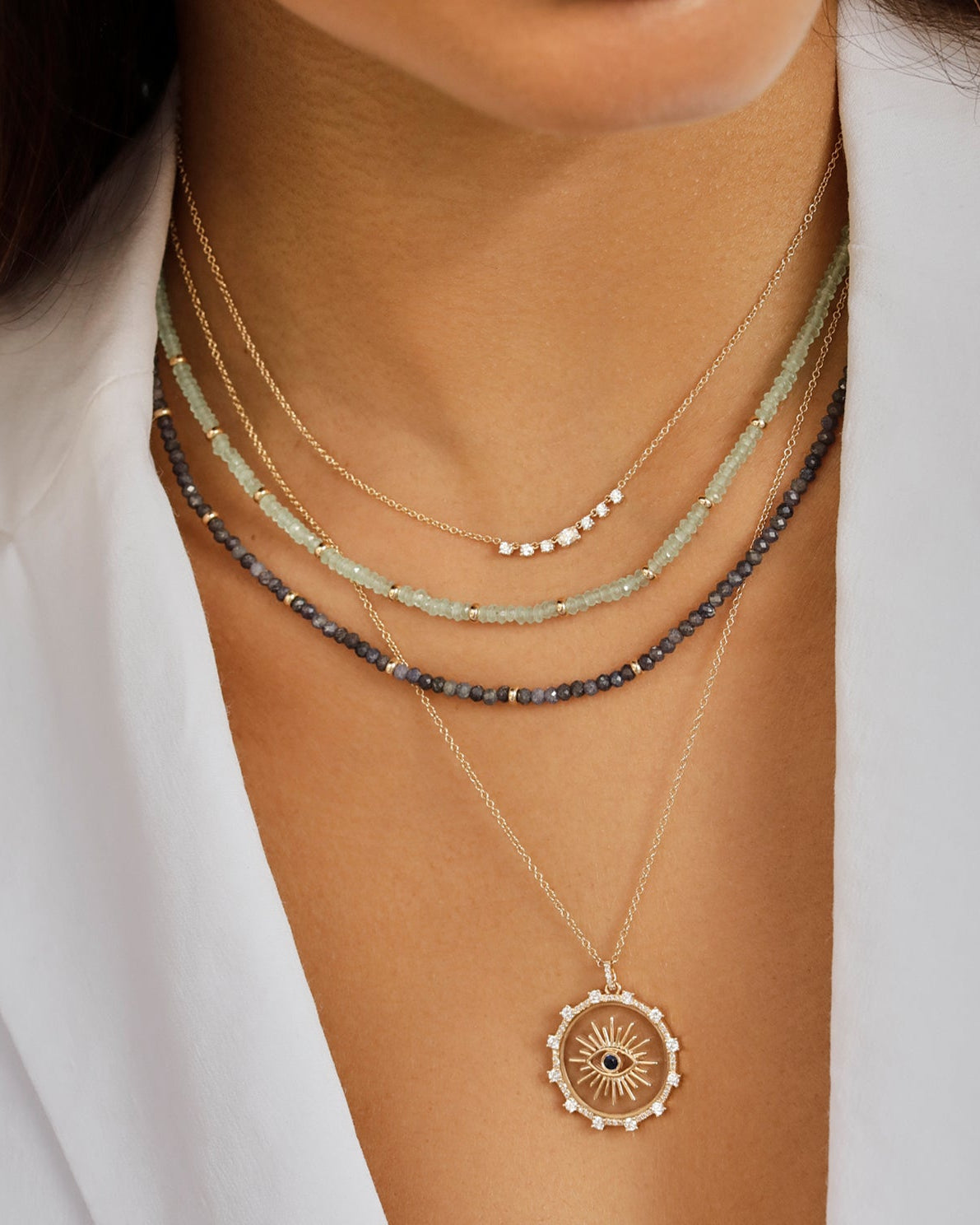 Diamond Carrie Necklace in 14k yellow gold styled on neck of model with birthstone bead and evil eye necklaces