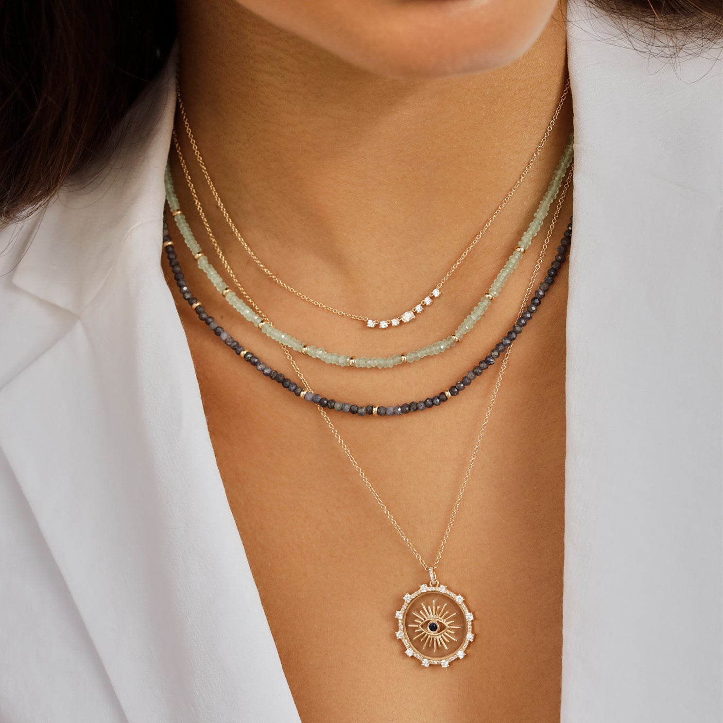 Diamond Carrie Necklace in 14k yellow gold styled on neck of model with birthstone bead and evil eye necklaces