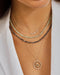 Diamond Carrie Necklace in 14k yellow gold styled on neck of model with birthstone bead and evil eye necklaces
