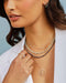 Diamond Carrie Necklace in 14k yellow gold styled on neck of model with birthstone bead and evil eye necklaces