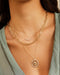 Floating Evil Eye Necklace in 14k yellow gold styled on neck of model with gold and diamond necklaces