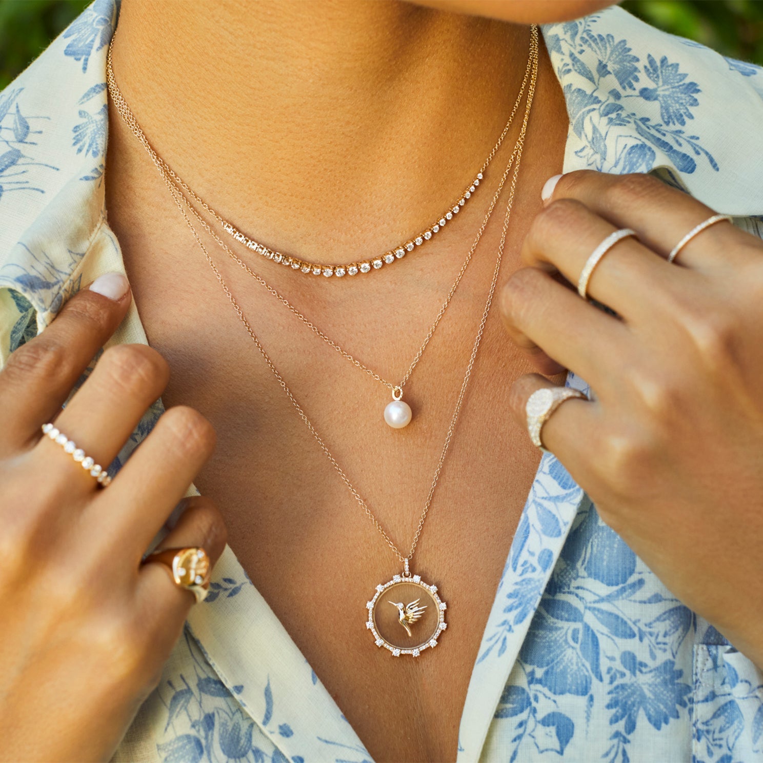 Pearl Ball Drop Necklace in 14k yellow gold styled on neck of model with diamond and hummingbird necklaces