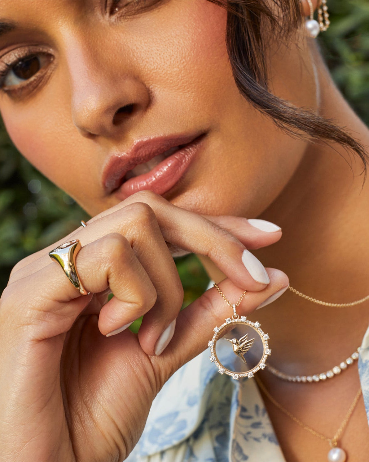 Floating Hummingbird Necklace in 14k yellow gold held in hand of model