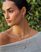 Pearl Ball Drop Necklace in 14k yellow gold styled on neck of model with diamond and hummingbird necklaces
