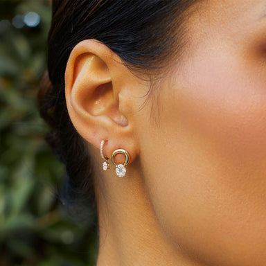 Oval Drop Diamond Mini Huggie Earring in 14k yellow gold styled on second earring hole of model
