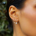 Oval Drop Diamond Mini Huggie Earring in 14k yellow gold styled on second earring hole of model