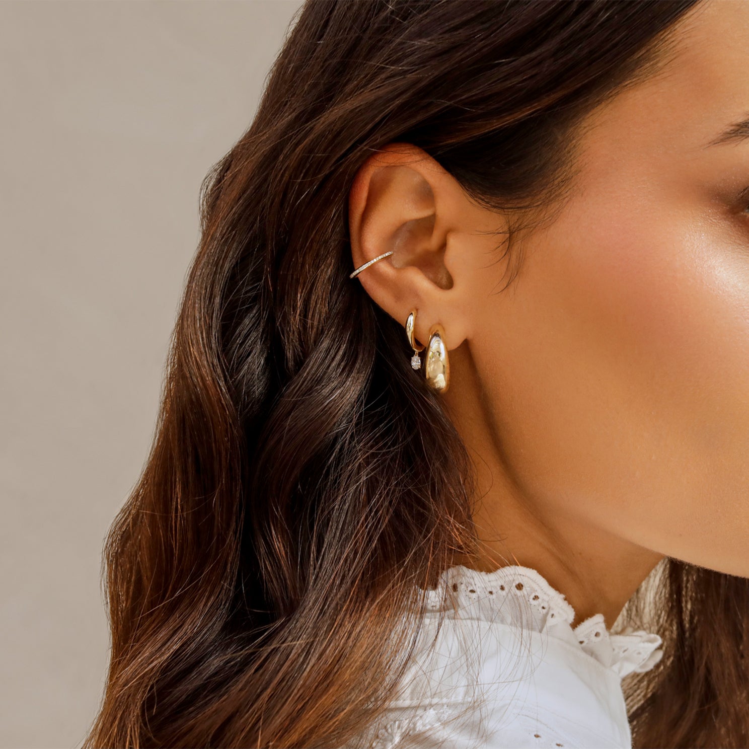 Diamond Oval Drop Gold Dome Huggie Earring in 14k yellow gold styled on second earring hole of model