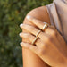 Diamond Pillow Stack Ring styled on middle finger of model with gold rings