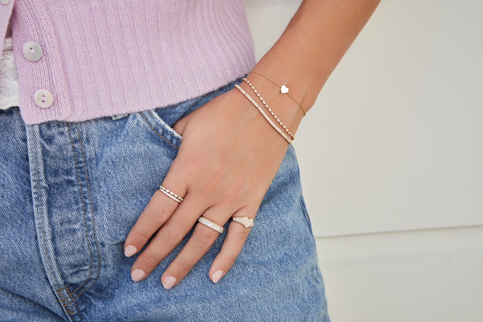 EF Collection 14k yellow gold rings and bracelets with diamonds styled on model in pink sweater