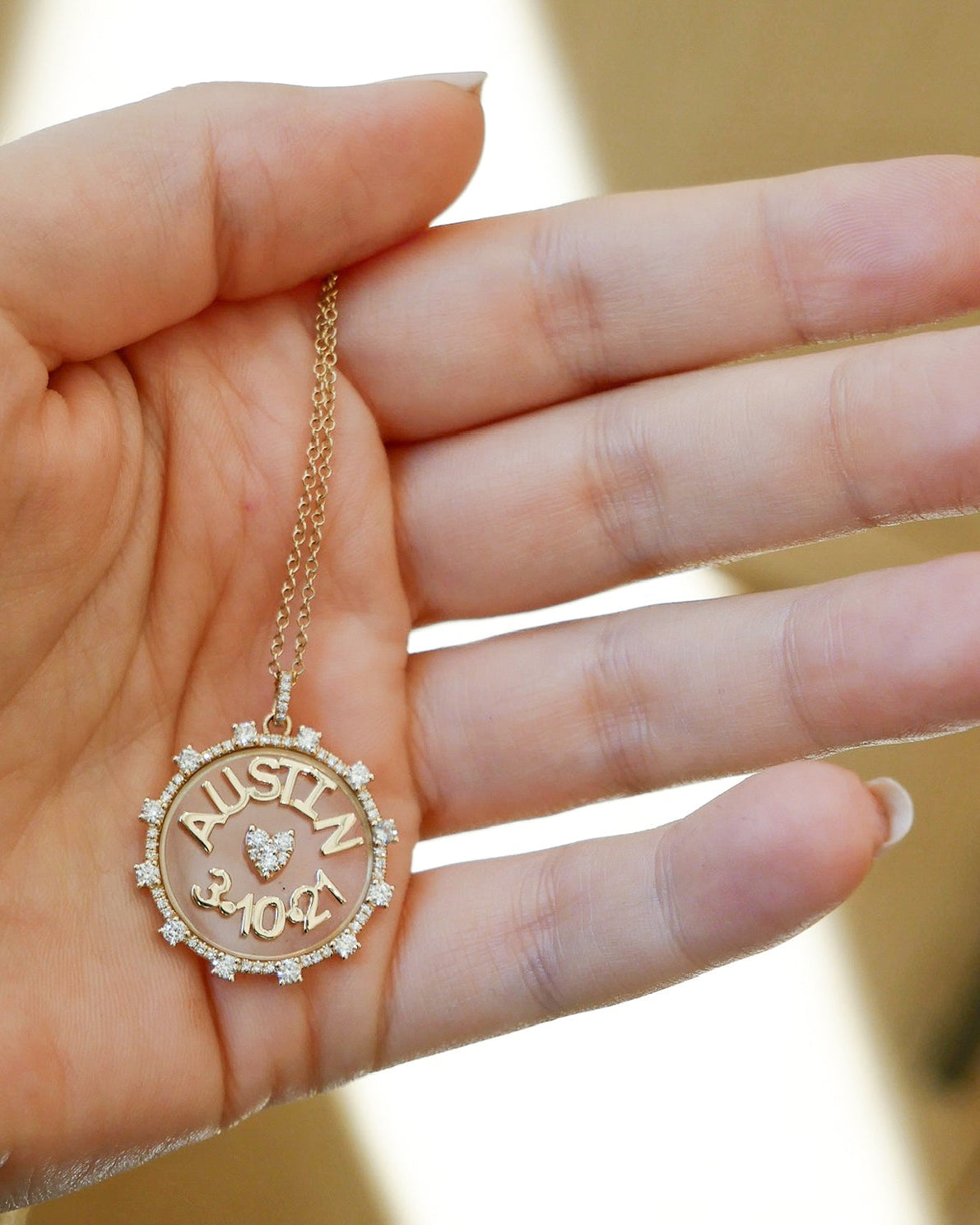 Floating Name & Date Necklace in 14k yellow gold with initials AUSTIN and date 3.10.21 held in hand of model