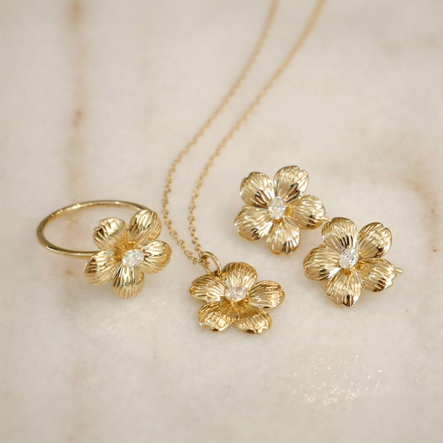 Cherry Blossom Ring in 14k yellow gold next to Cherry Blossom Necklace and Cherry Blossom Earrings