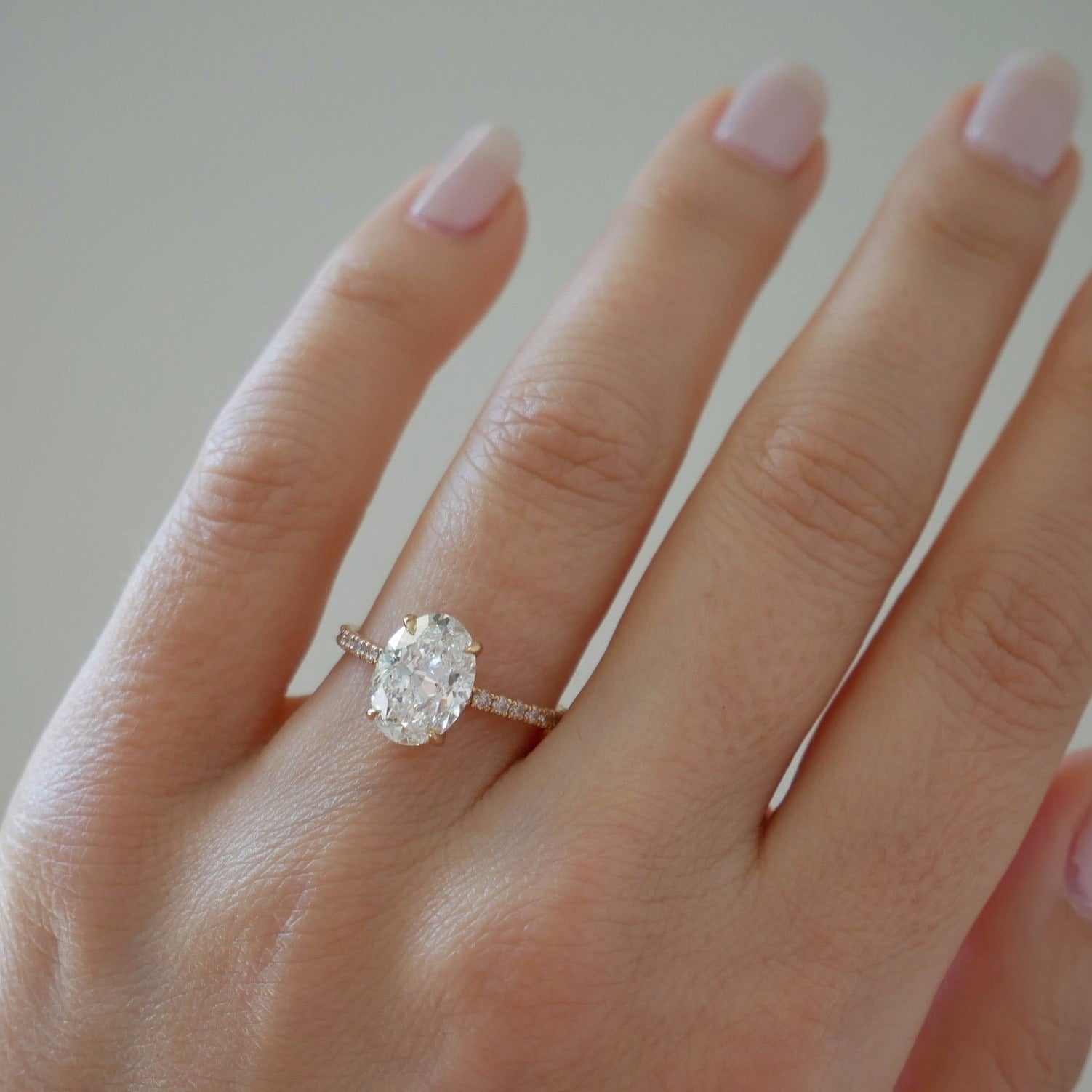 The Jessica Engagement Ring with oval center diamond and micro pave diamonds on rose gold band on ring finger of model