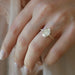 The Jessica Engagement Ring with oval center diamond and micro pave diamonds on rose gold band styled on ring finger of model