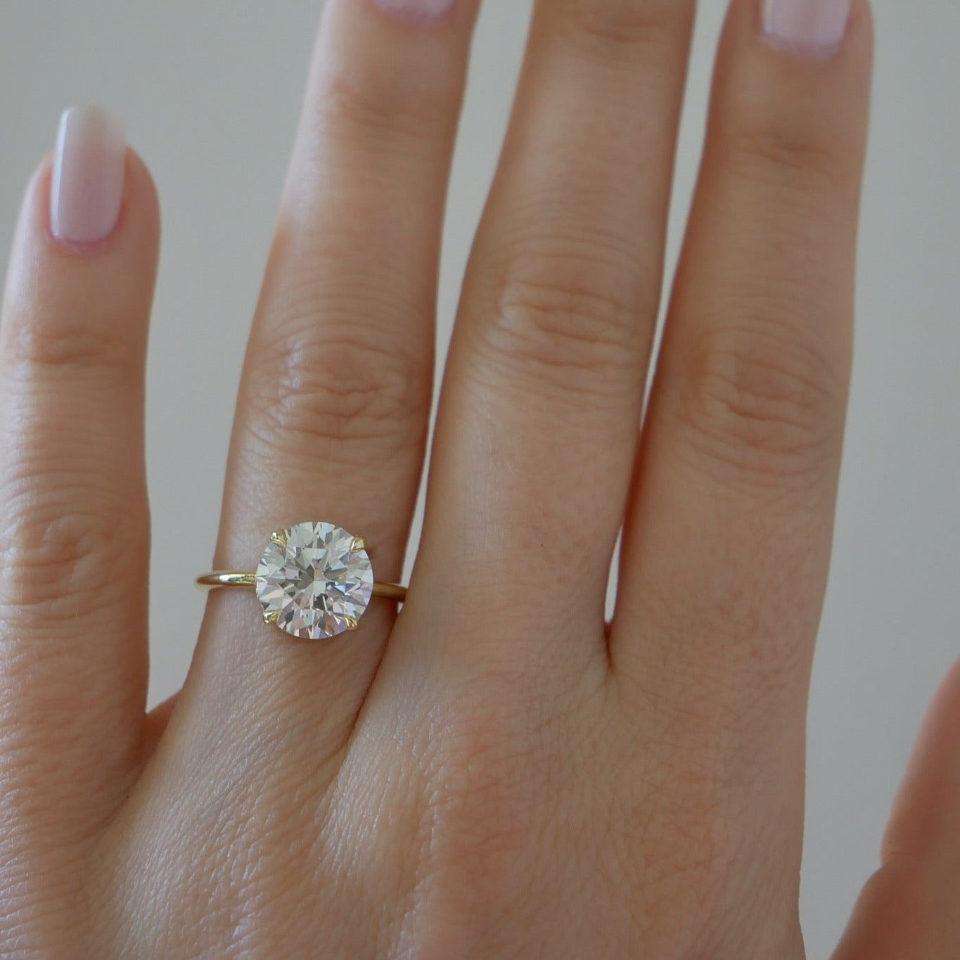 The Lindsay Engagement Ring with round center diamond and yellow gold band styled on ring finger of model
