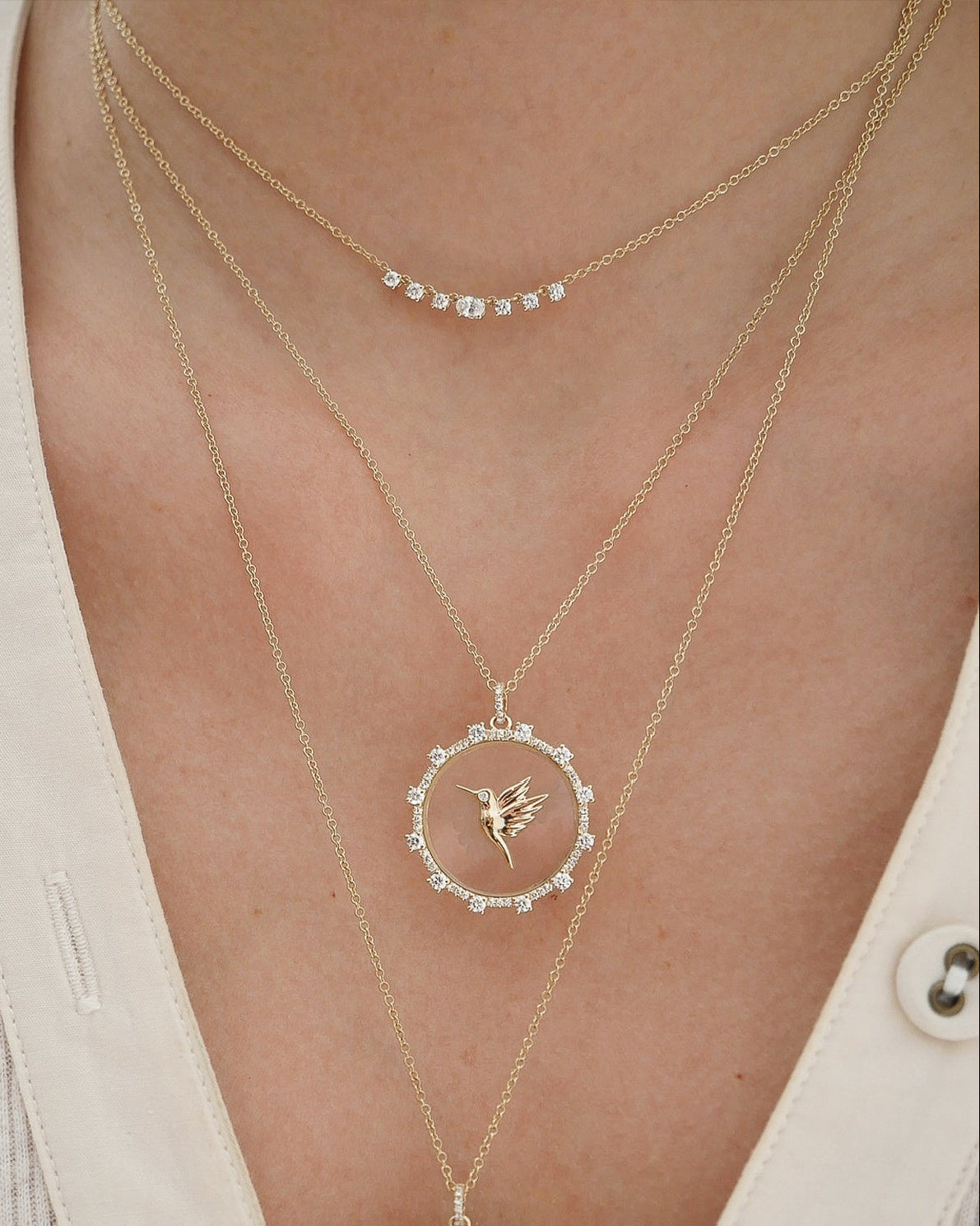 Floating Hummingbird Necklace in 14k yellow gold styled on neck of model with diamond necklace