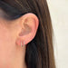 Double Diamond Baguette Illusion Mini Huggie Earring in 14k yellow gold styled on ear of model