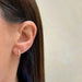 Diamond Pointed Huggie Earring in 14k yellow gold styled on first earring hole of model next to diamond stud earring
