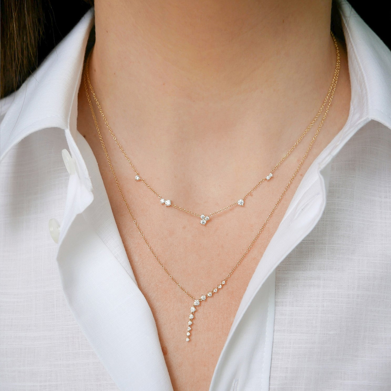 Multi Diamond Cluster Necklace in 14k yellow gold styled on neck of model with diamond waterfall necklace with model in white blouse