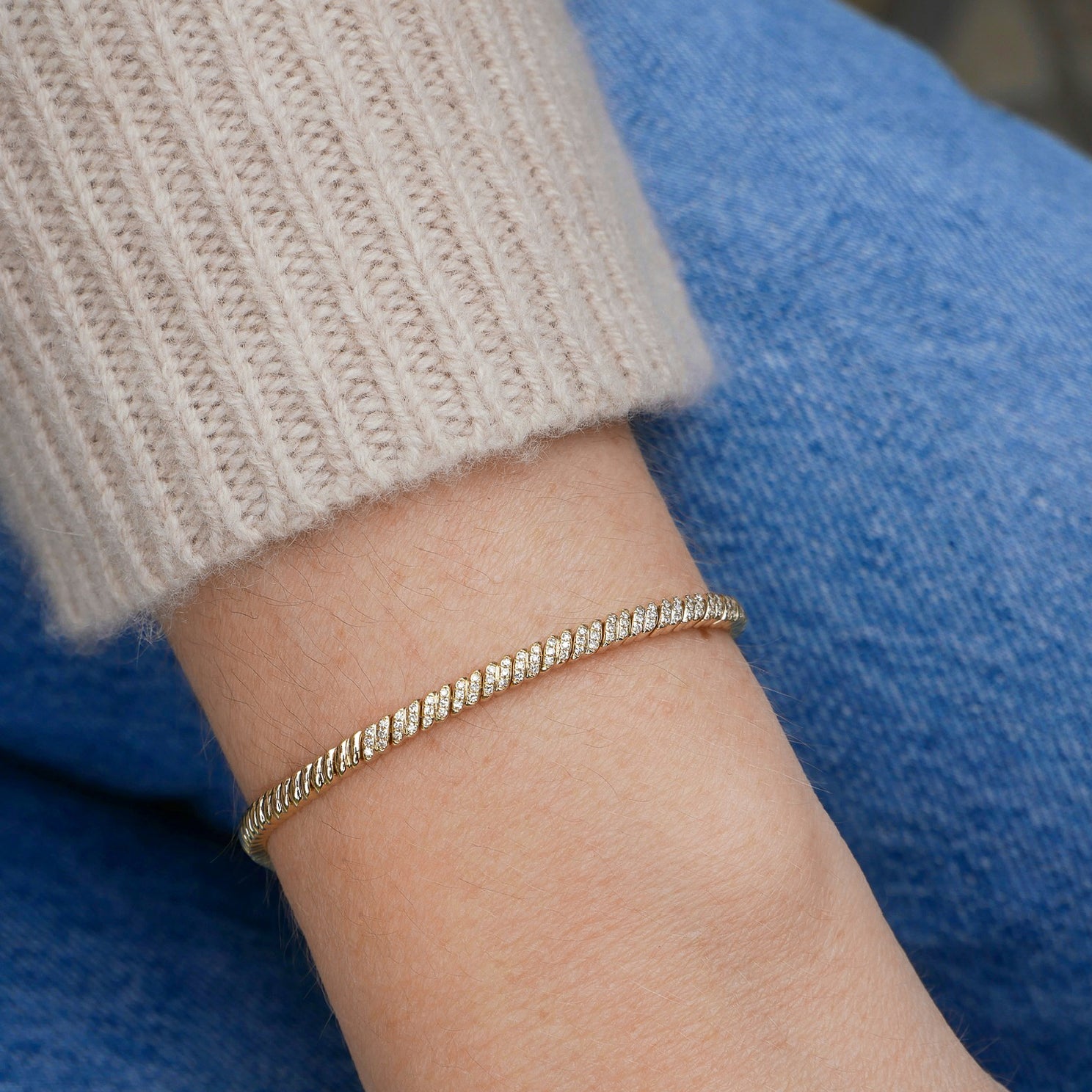 Diamond Twist Bracelet in 14k yellow gold styled on wrist of model with sweater sleeve