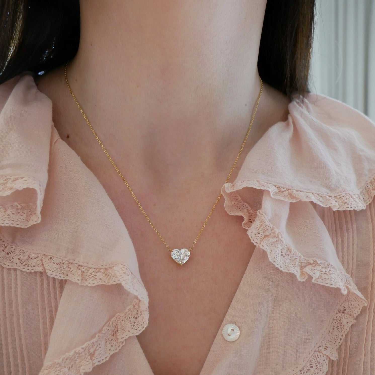 Diamond Heart Solitaire Necklace with 3 carat diamond with yellow gold chain styled on neck of model in pink blouse