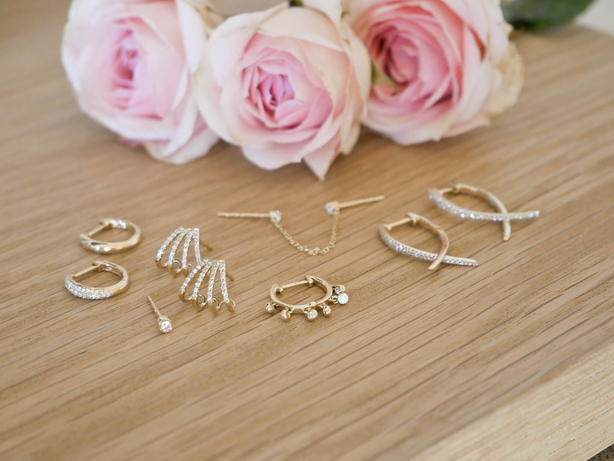 EF Collection 14k yellow gold earrings with diamonds next to pink roses