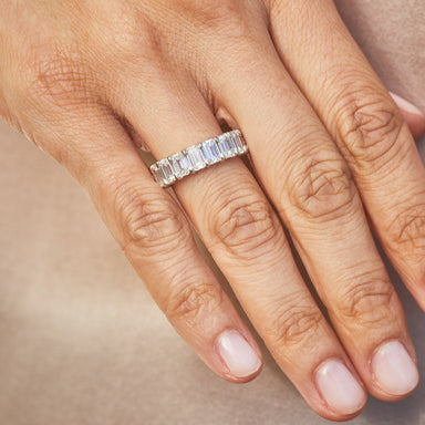 Emerald Cut Diamond Eternity Band in platinum setting styled on ring finger of model