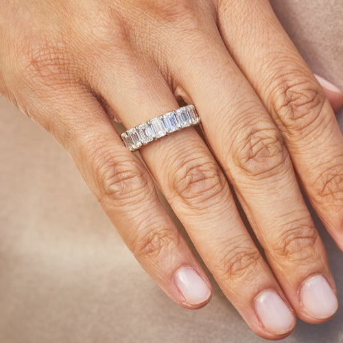 Emerald Cut Diamond Eternity Band in platinum setting styled on ring finger of model
