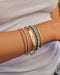 Nameplate Jumbo Link Bracelet in 14k yellow gold engraved with initials EMILY in script font styled on wrist of model with gold, diamond, and birthstone bead bracelets
