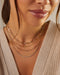Gold and diamond necklaces styled on neck of model wearing tan sweater