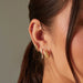 Baby Solitaire Diamond Stud Earring in 14k yellow gold styled on ear lobe of model with diamond and yellow earrings