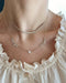 Full Cut Heart Double Diamond Script Name Necklace with names Nasya and Nayet with heart in the middle of necklace styled on neck of model with diamond segment necklace