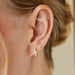 Baby Solitaire Diamond Stud Earring in 14k yellow gold styled on ear of model with three diamond earrings