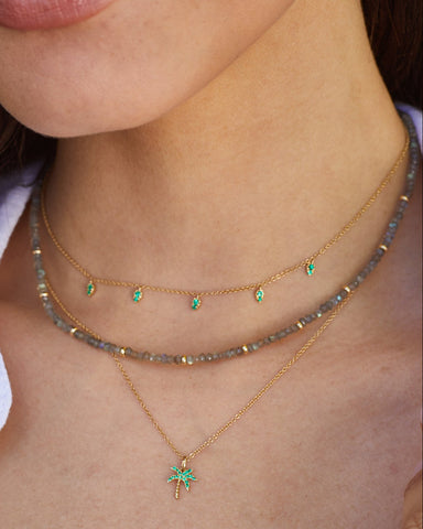 Emerald 5 Teardrop Choker Necklace in 14k yellow gold styled on neck of model with emerald palm tree necklace and beaded necklace