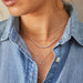 Graduated Diamond Necklace in 14k yellow gold styled on neck of model with three gold necklaces